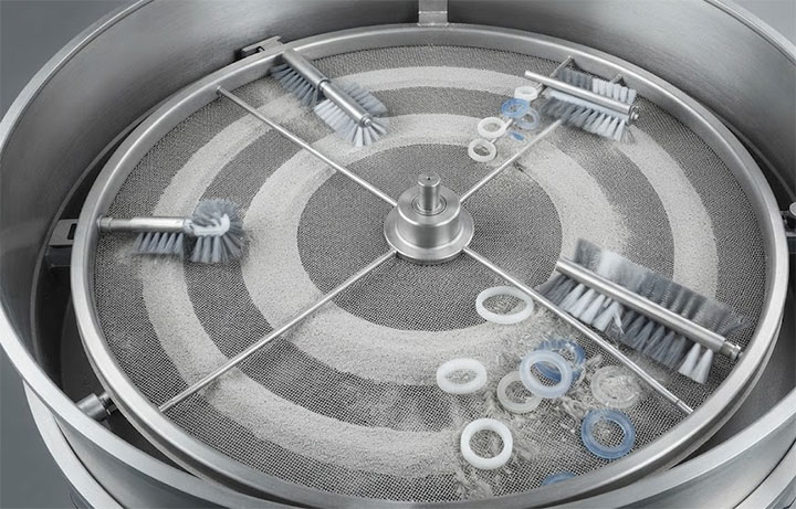 Top view of tumbler screener internal deck featuring rotating cleaning brushes and bouncing rings for screen clearing